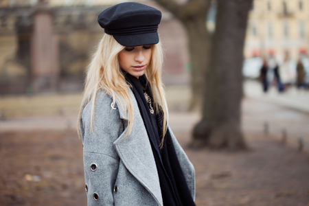 Young, hip and attractive blonde walking around the city, girl in a stylish hat and a gray coatの写真素材