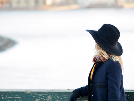 Young woman in hat and coat walking. Portrait of the blonde on the street, smiling and funの写真素材