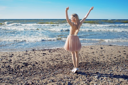 Young cheerful girl on the seashore. Young blonde woman smiling. Trendy beige skirtの写真素材