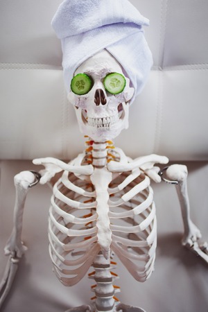 Skeleton in Spa salon with towel on her head and mask on her face, relaxes. An absurd concept, social parody. Take care of beauty and forget about inner peaceの写真素材