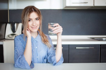 Attractive young woman drinking water in the kitchen. Habits for a healthy lifestyleの写真素材