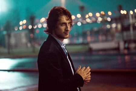 Young stylish guy on the background of night city, city lightsの写真素材