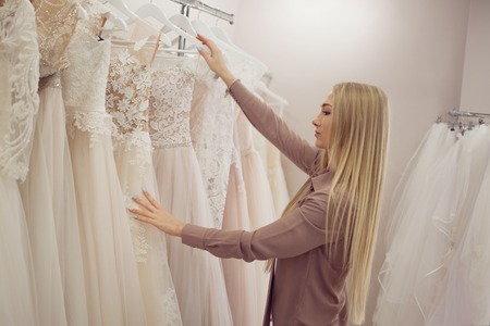 Beautiful girl chooses her wedding dress. Young woman entrepreneur. Portrait in Bridal salonの写真素材