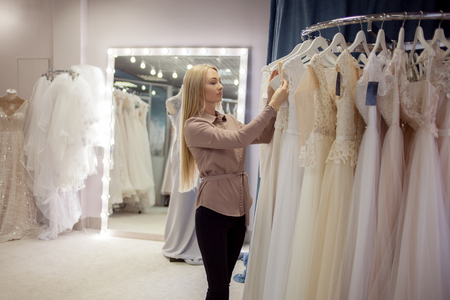 Beautiful girl chooses her wedding dress. Young woman entrepreneur. Portrait in Bridal salonの写真素材
