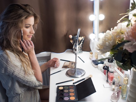 Portrait of a beautiful girl in the bedroom in front of mirror. Morning to do makeupの写真素材