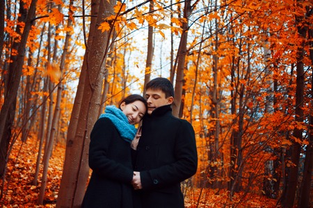 Young couple in autumn Park. Cute guy and a girl walking togetherの写真素材