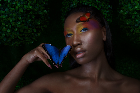 Young and beautiful black model, exotic look with bright blue butterfly