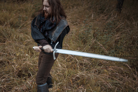 Battle. Knight in the forest. A guy in medieval costume with a swordの写真素材
