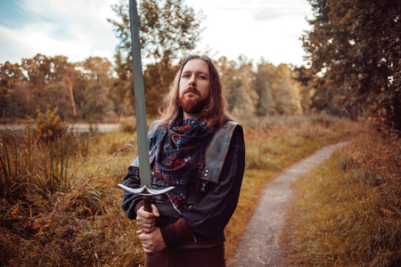 Bearded man knight. A guy in a medieval costume with a swordの写真素材