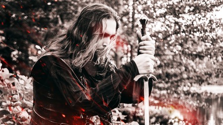 Knight with a sword bowed the knee, effect of fire and toningの写真素材