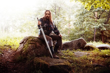 Knight on the road. A guy in a medieval costume with a swordの写真素材