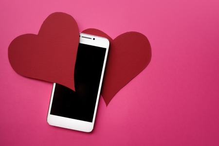Hearts and smartphone. The concept to like in social networks or Dating app. pink backgroundの写真素材
