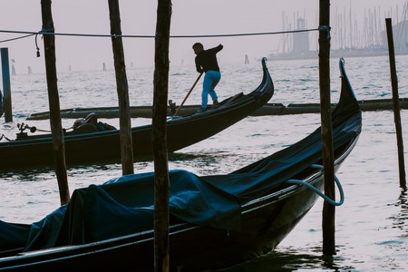VENICE, ITALY - OCTOBER 6 , 2017: Gondolier gives mooring lines with San Giorgio di Maggiore church on the backgroundのeditorial素材