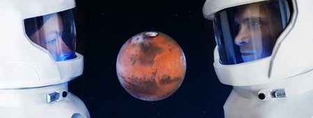 The development of Mars, concept. Two astronauts, a man and woman looking at the planet Mars.