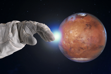 The development of Mars, concept. Hand of astronaut reaches out to Mars.の写真素材