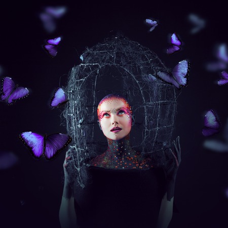 Soul breaks free from the cage. Young attractive girl in bright art-makeup, a lot of butterfliesの写真素材