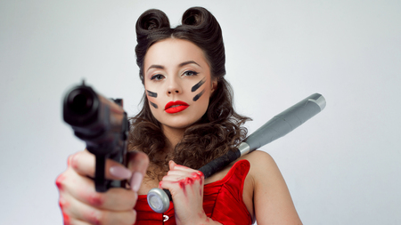 Woman in red with a gun and a bat in war paint, girl powerの写真素材