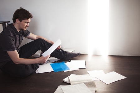 Young male entrepreneur makes brainstorming sitting on the floor in the apartment. Creative approach to businessの写真素材