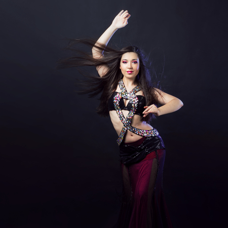 Beautiful girl in crimson dress dancing Oriental danceの写真素材