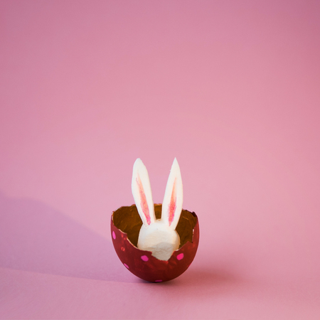 Easter concept. Colored eggs on a pink background, Easter Bunny hiding inside
