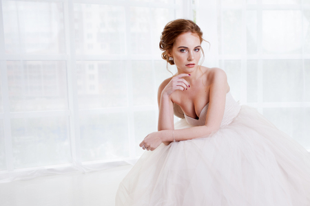 Portrait of a beautiful girl in a wedding dress. Bride in a luxurious dress on a white backgroundの写真素材
