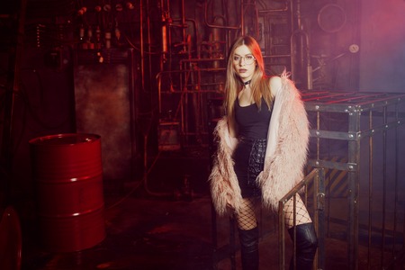 Young attractive woman with stylish clothes. Beautiful girl in a fluffy pink fur coat, cyberpunk background. Neon lightの写真素材