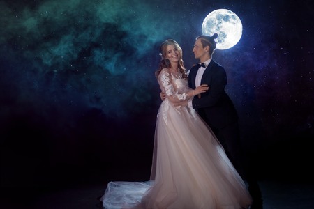 Mysterious and romantic meeting, the bride and groom under the moon. Hugs together. Man and woman, wedding dress. Mixed mediaの写真素材