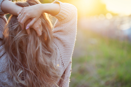 Cute charming girl in summer in the field. Young woman is happy and feels free, outdoors. Back viewの写真素材