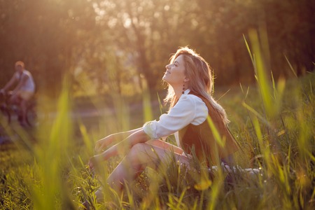 Beautiful young woman enjoying a picnic in nature. Girl sitting on the grass, rest, relaxationの写真素材