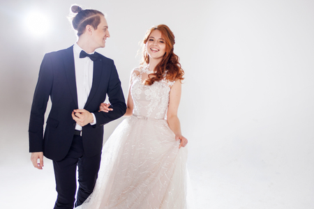Positive young couple laughing and dancing together. The couple in the Studio a light background. Boyfriend and girlfriend, costume and wedding dressの写真素材