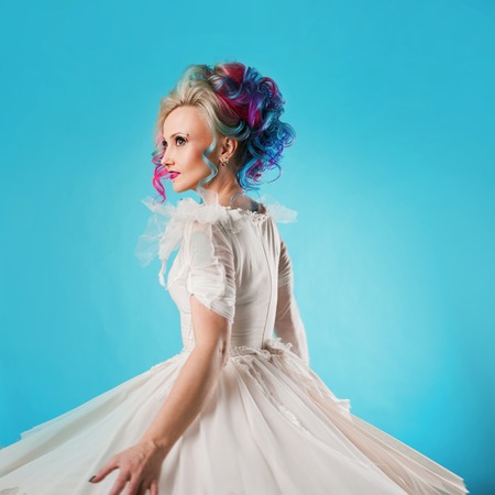 Cool young woman with colored hair. Stylish hairstyle, informal style. Blue backgroundの写真素材