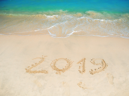 Sea surf. A blue wave is coming ashore. Inscription on the sand, celebrate the new year in the...