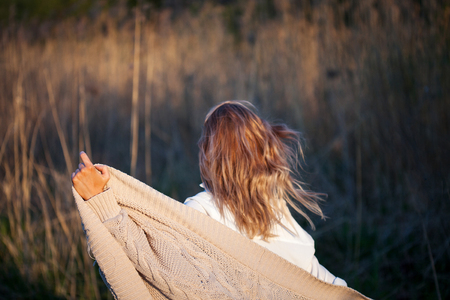 Cute charming girl in summer in the field. Young woman is happy and feels free, outdoors. Back viewの写真素材