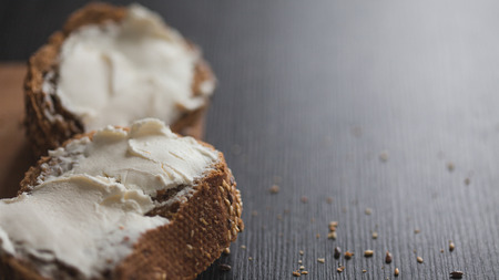 Two sandwiches of multi-grain bread with cream cheese. Close-up, free space for text. Black backgroundの写真素材