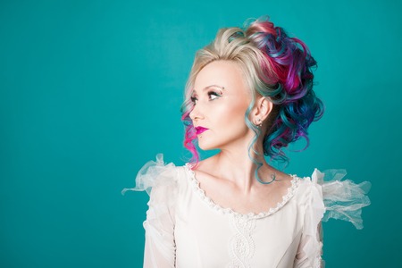 Beautiful woman with creative hair coloring. Stylish hairstyle, informal style. Blue background