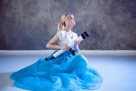 Young woman dreams of the future, concept. Girl looks up and uses a telescope. Dream and set goals, look through the telescope. Grey textured backgroundの写真素材