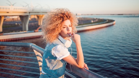 Beautiful and cheerful young woman with lush hair, outdoors. Youth styleの写真素材