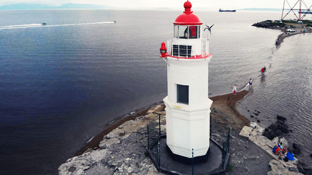 Top view of the lighthouse standing in the sea. Copy space, small lighthouse with red roof, drone photoの写真素材