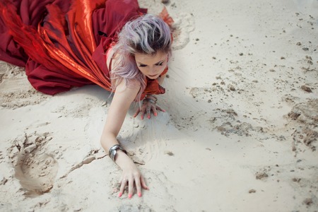 Oriental dance. Beautiful woman sitting on the sand, hands with bracelets on the sand. Free space on the rightの写真素材