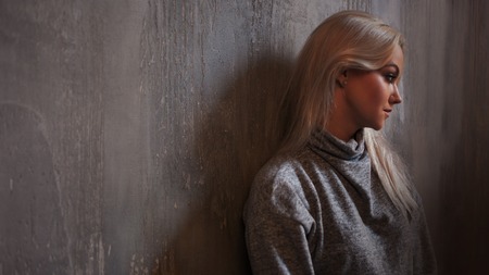 Depressed woman. blonde girl sitting on the floor, sadness and depression, concept of psychological problemの写真素材