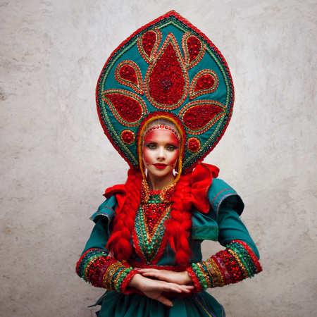 Girl in a headdress. Portrait of a beautiful young woman in a stylized Russian suitの写真素材