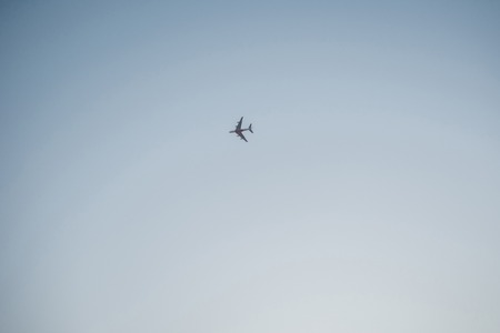 Flying plane high in the sky, a small silhouette against the cloudsの写真素材