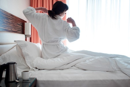 young woman in a white Terry robe woke up this morning. in the hotelの写真素材