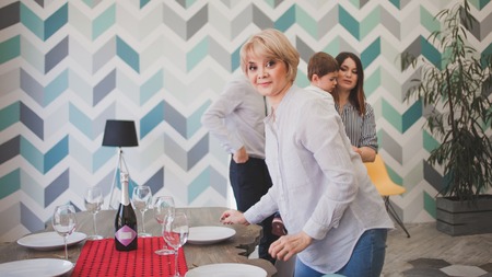 Family dinner. Family receives guests, a festive meeting. family serves table and communicates with each other. Parents children and grandchildren in the house, cake on table.の写真素材