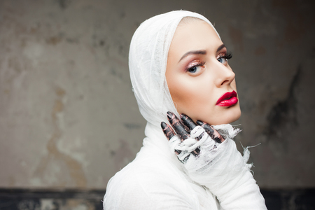 Glamorous mummy. Portrait of a young beautiful woman in bandages all over her body. Halloween or plastic surgery conceptの写真素材