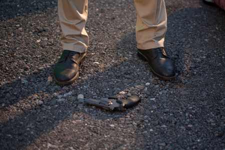 Detective at the crime scene. A man stands over the victim's body. Crime, murder outdoorsの写真素材