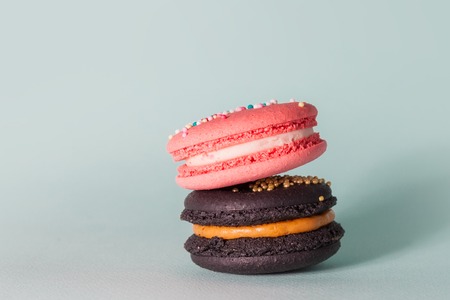 Bright delicious macaroons. French sweets. Pink and black cake on light blue background