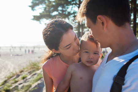 Portrait of happy young family with charming baby. Picnic on the beach, mom dad and sonの写真素材