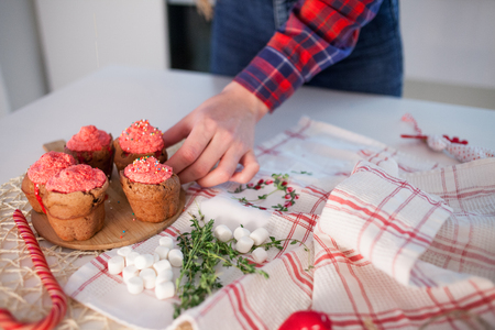 Girl decorates  celebration cupcakes, chocolate muffins on table. The girl's hand reaches for home cupcakesの写真素材