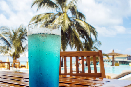 glass with a bright blue drink on the table on the hotel terrace. Luxury resort on tropical iseland.の写真素材